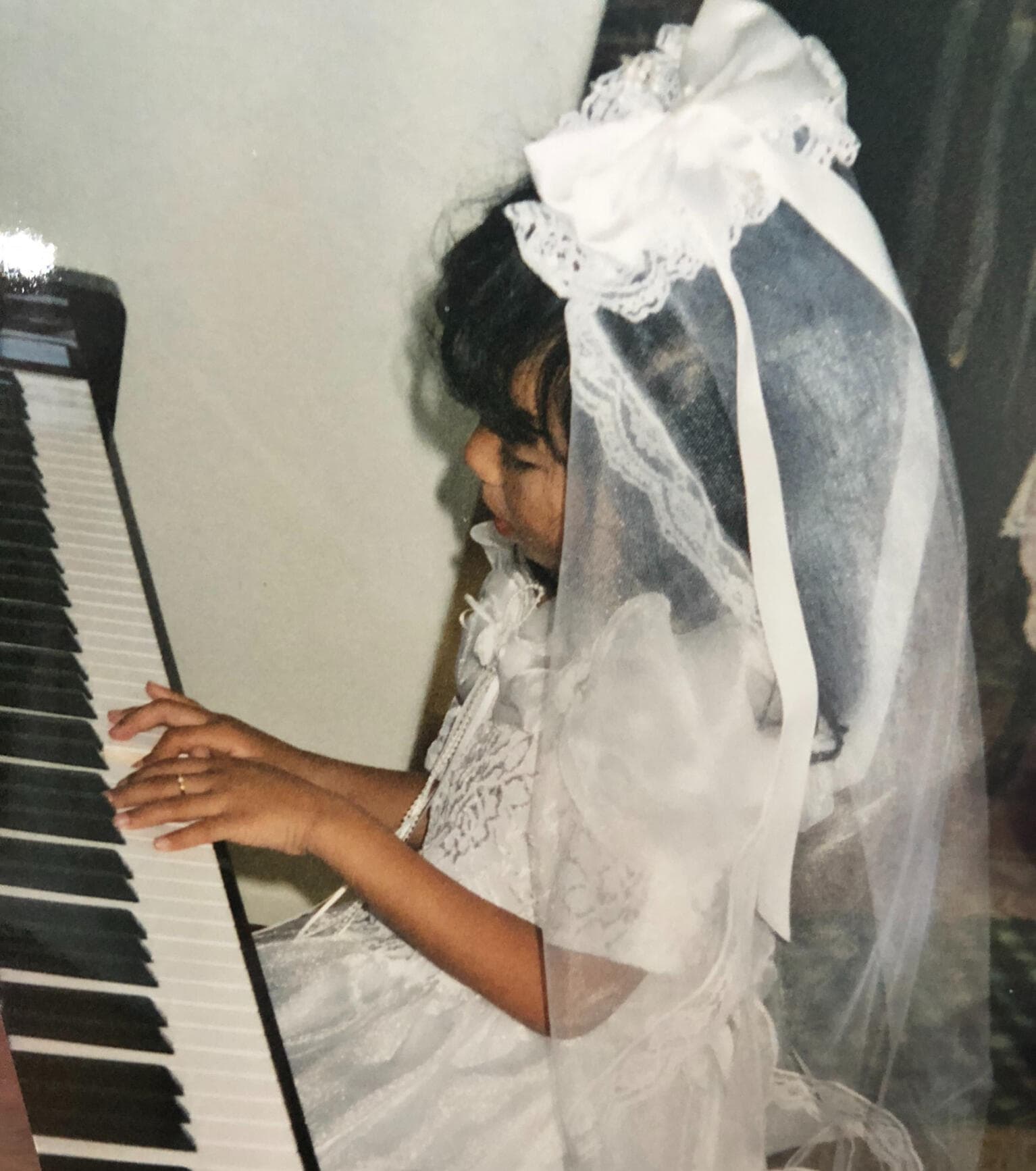 A young Ambergrace at the piano in her First Communion dress
